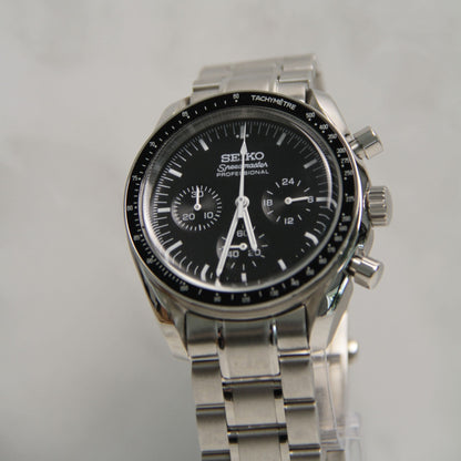 Montre Seiko mod speedmaster noir vu de face sur coussin